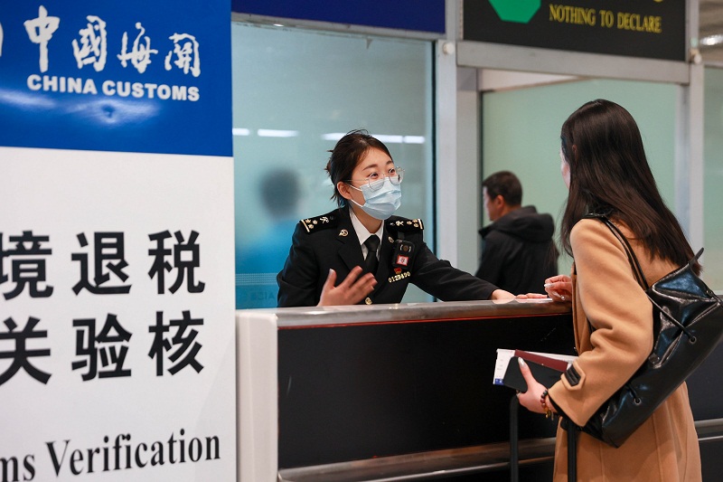 2-首都机场海关关员向旅客宣传离境退税政策和办理流程。撰稿摄影舒善